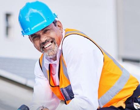 Man on roof with drill and hardhat